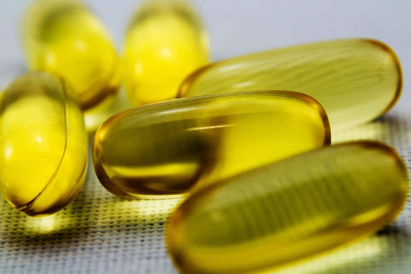 a group of yellow fish oil capsules on a cloth.