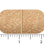 A brown, speckled oblong tablet of Vitakruid – Multi Day & Night® Mama (2 x 30 Tablets) is displayed on a scale, measuring approximately 2 centimeters wide and 1 centimeter tall.