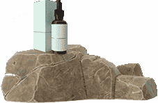 A small dropper bottle and a rectangular box are placed on top of a textured rock surface.